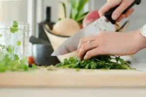 a person cutting parsley on a cutting board