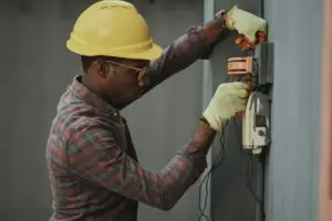 a man wearing a hard hat and gloves working on a switch