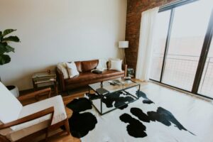 a living room with a leather couch and cow hide rug