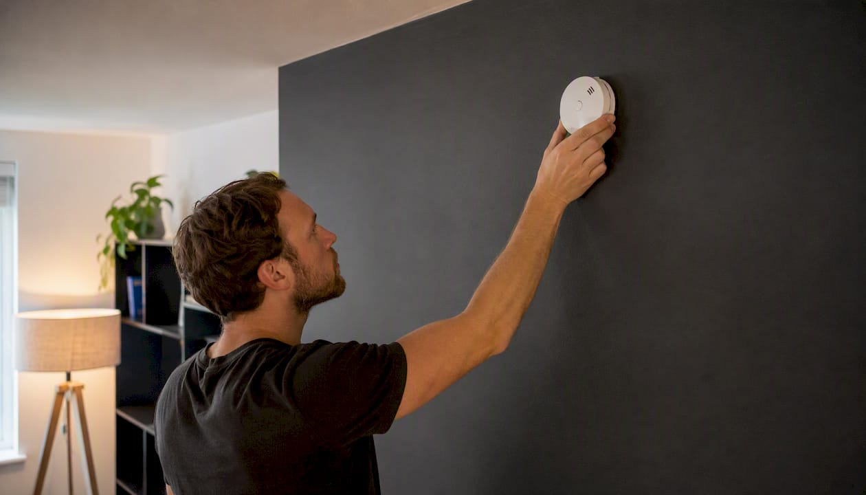 Hand installing CO alarm near ceiling