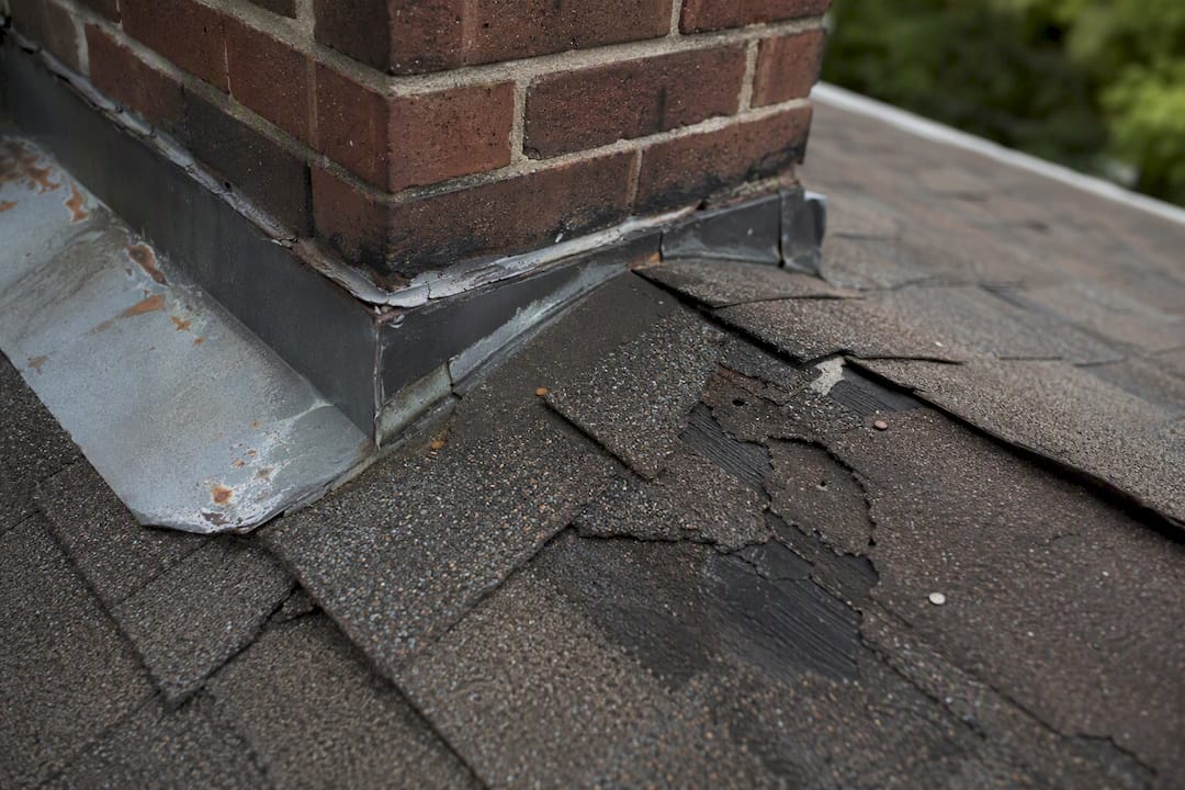 Close-up of damaged roof shingles and flashing