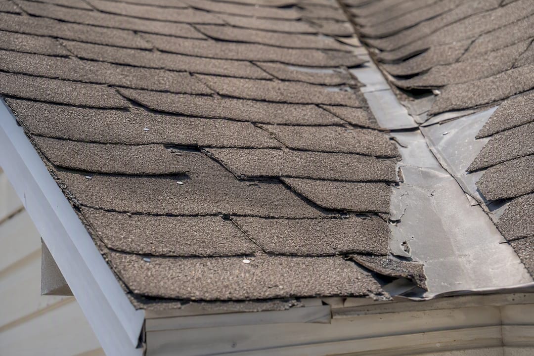 Close-up of roof installation defects on shingles and flashing