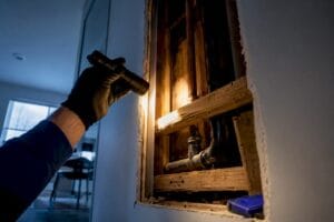 Inspector examining concealed plumbing inside wall