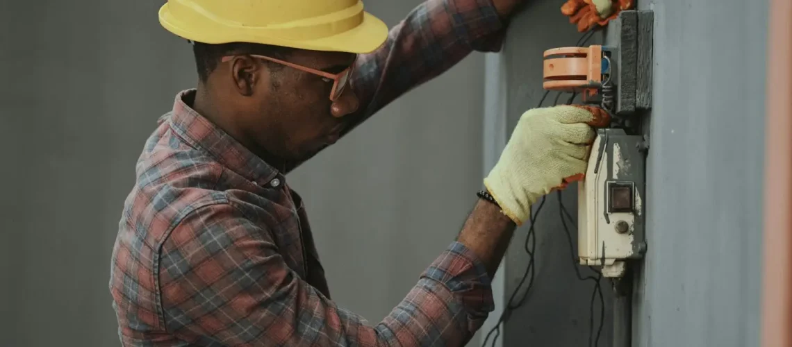 a man wearing a hard hat and gloves working on a switch