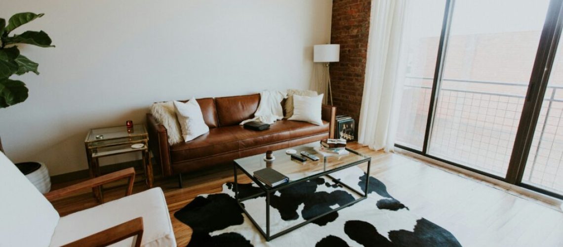 a living room with a leather couch and cow hide rug